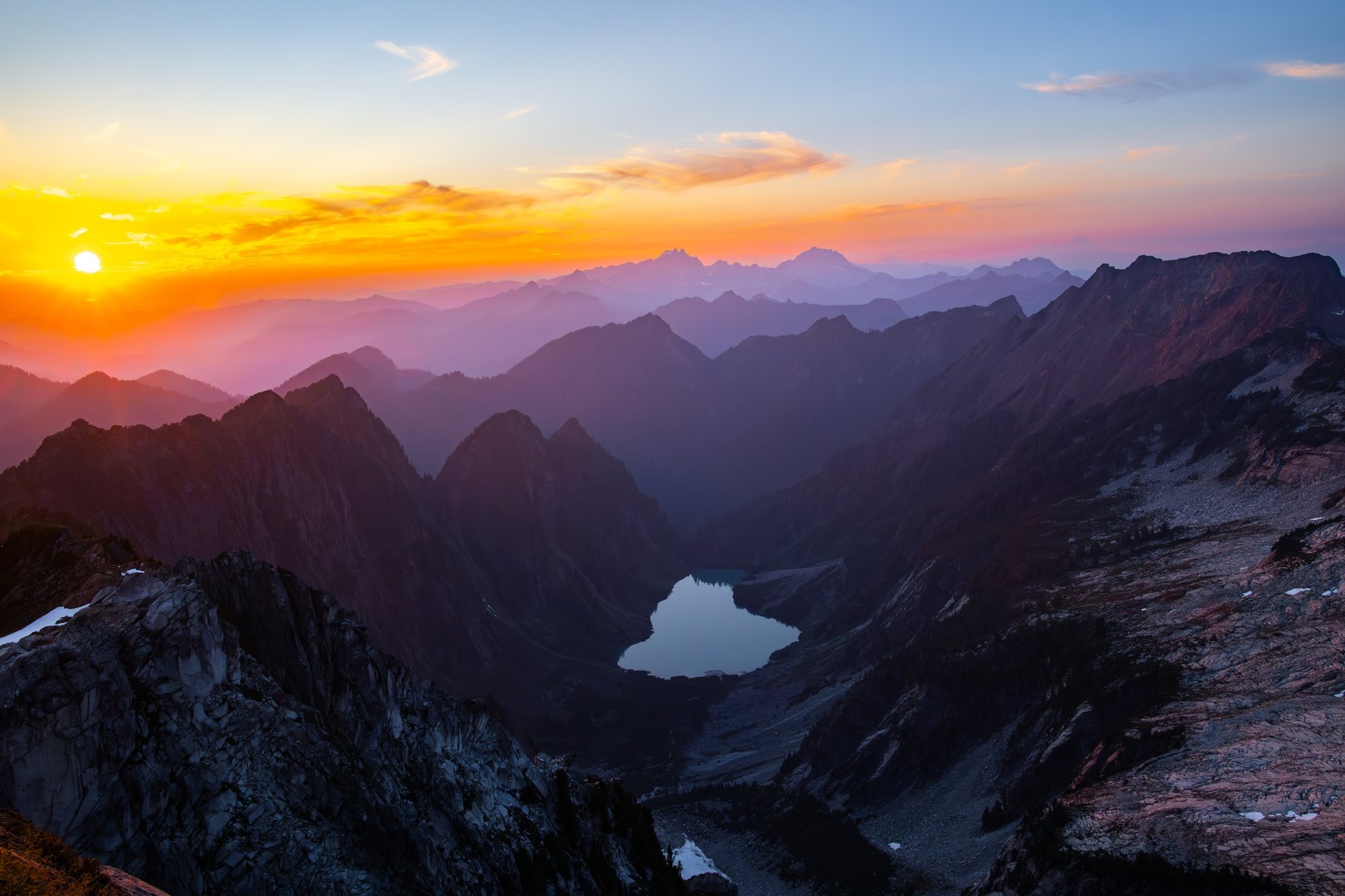 Sunset over jagged alpine peaks and a lake in the North Cascades
