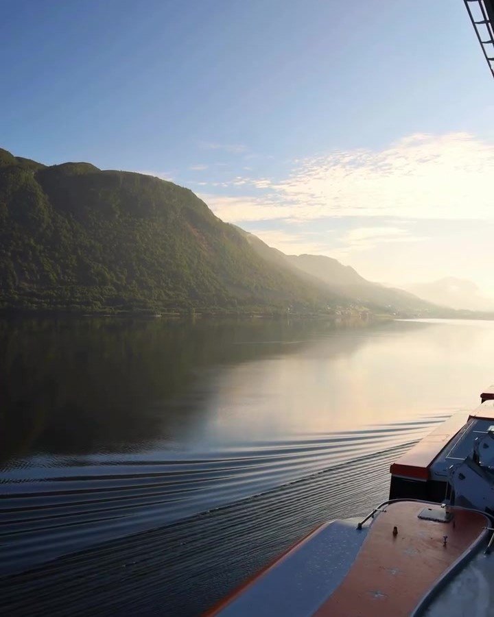 View from a cruise ship deck across a Norwegian fjord in evening light