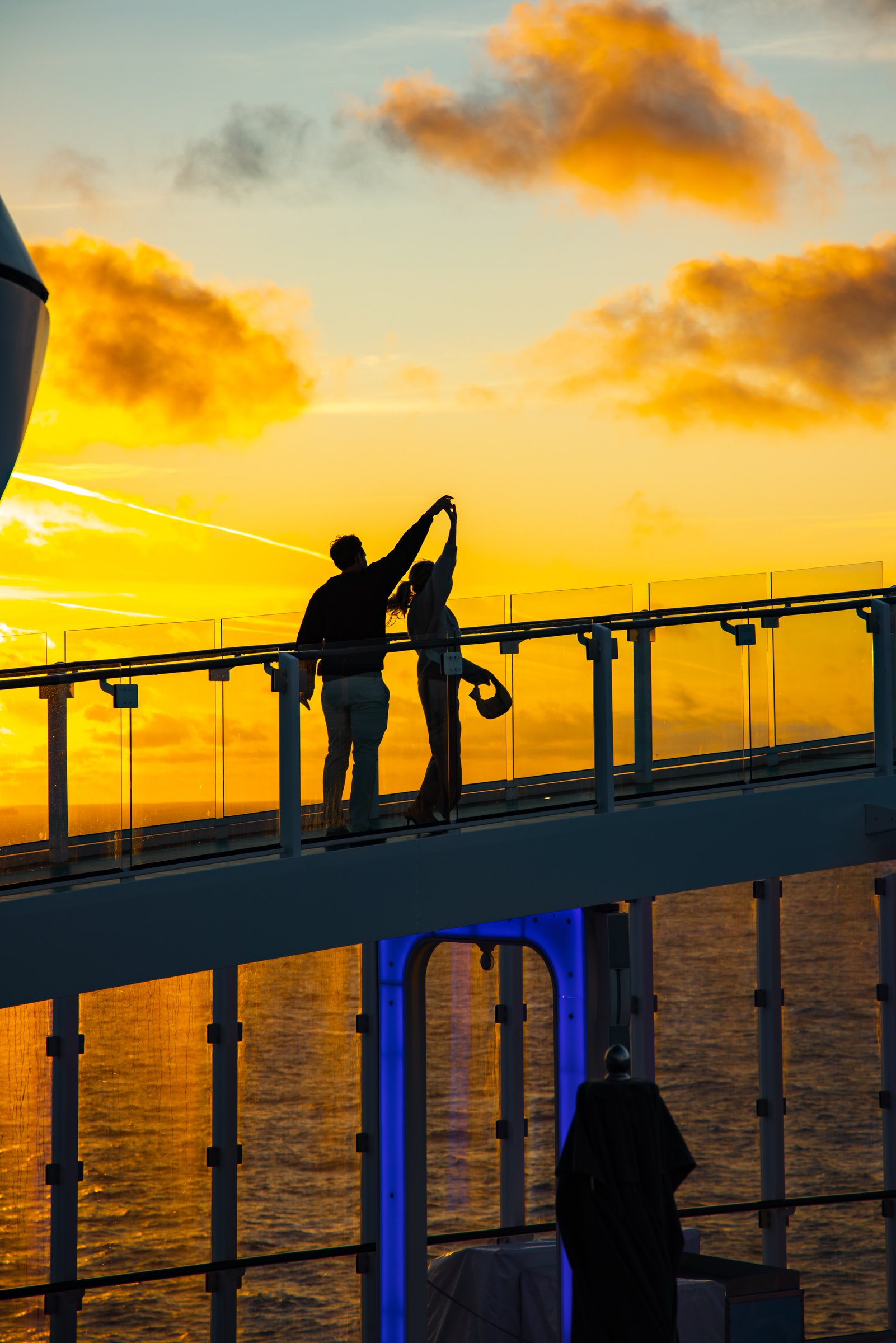 Couple silhouetted dancing on the deck of a cruise ship against a golden sunset
