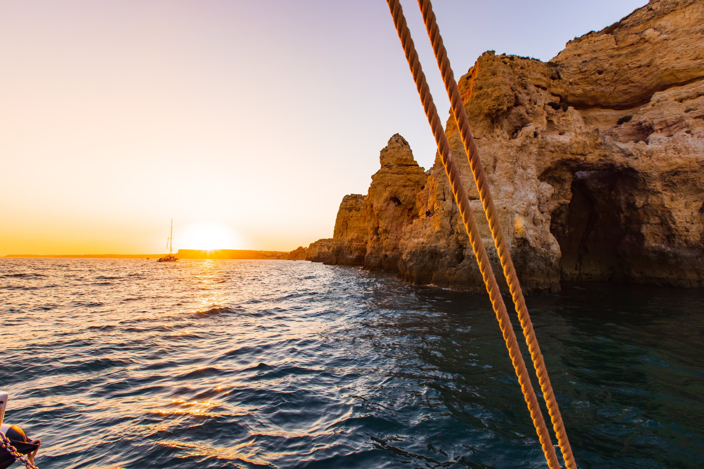 Sunset over the ocean beside golden sea cliffs, seen from a sailboat in Lagos