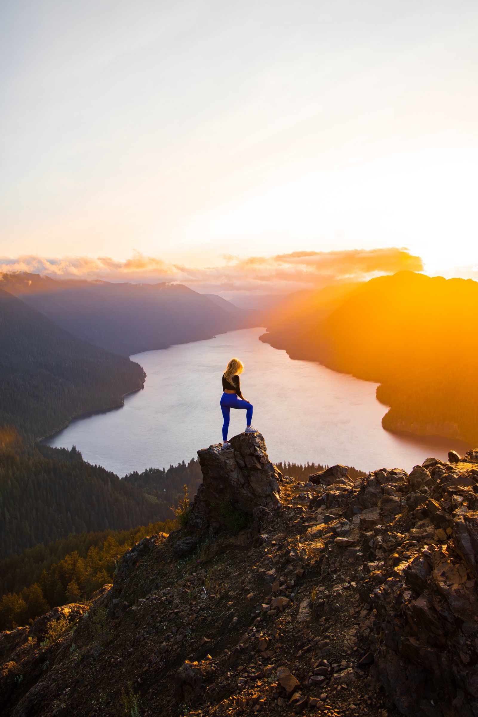 Hiker standing on a rocky summit above Lake Crescent at golden sunset, Mount Storm King