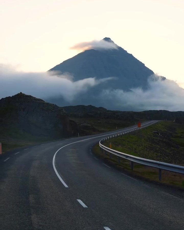 Winding road beneath a cloud wrapped mountain in Iceland
