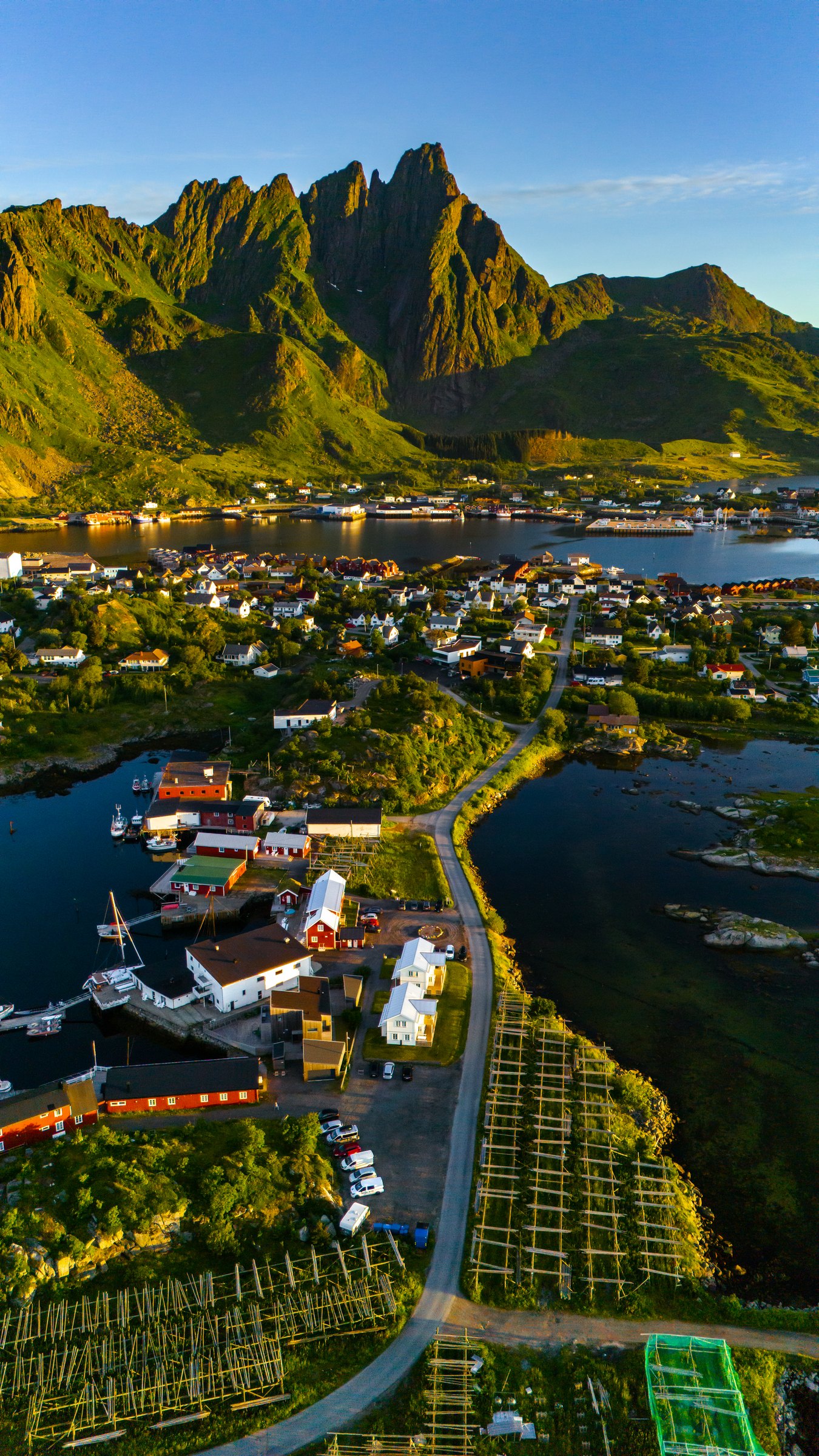 Aerial of a Lofoten fishing village between green peaks and the sea in Norway