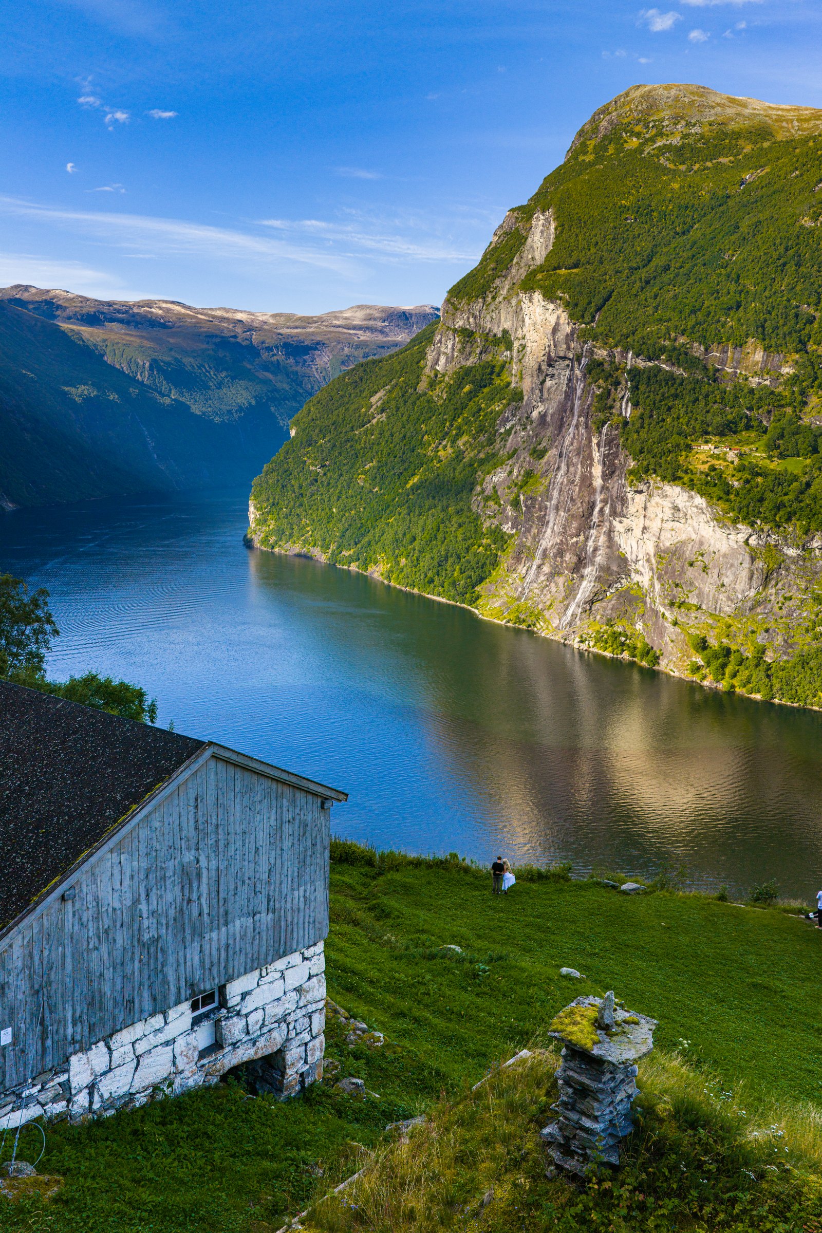 Old farmhouse on a green hillside high above the Geirangerfjord and its cliffs