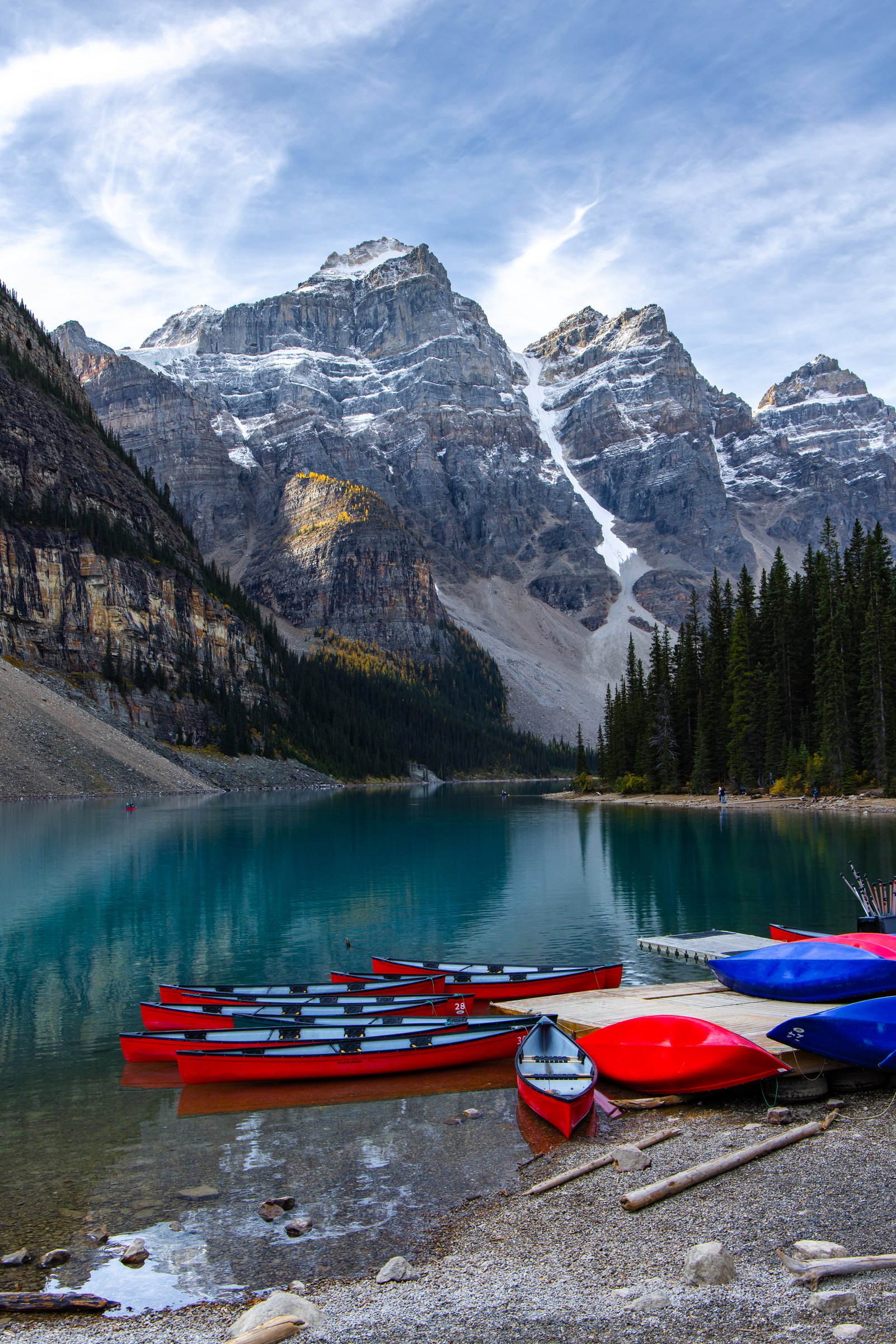 Red and blue canoes on the shore of turquoise Moraine Lake below jagged peaks