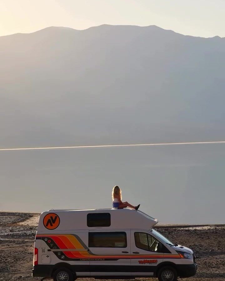 Travellers Autobarn campervan beside water with mountains beyond
